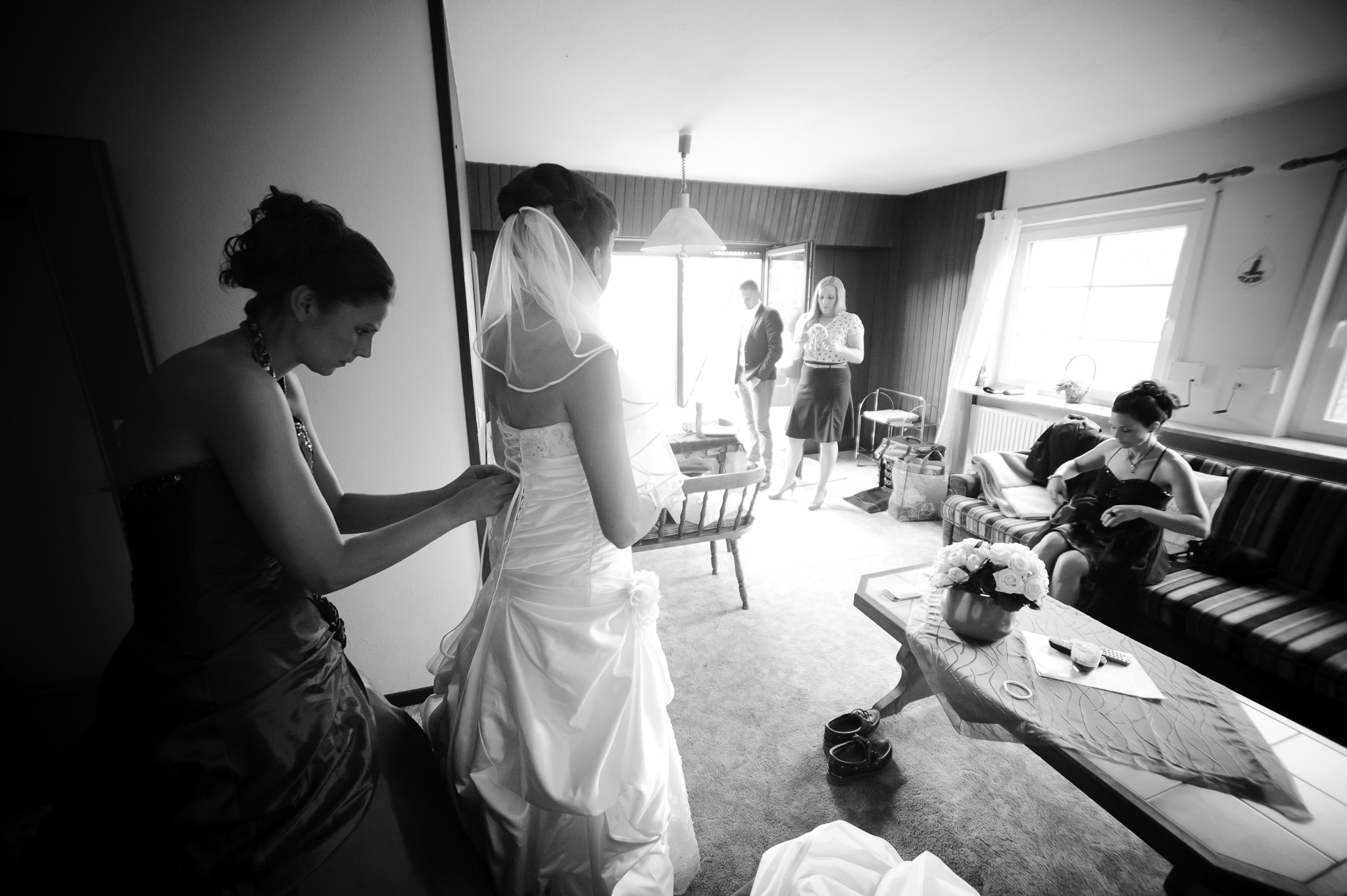 Braut mit weiteren Personen beim Ankleiden